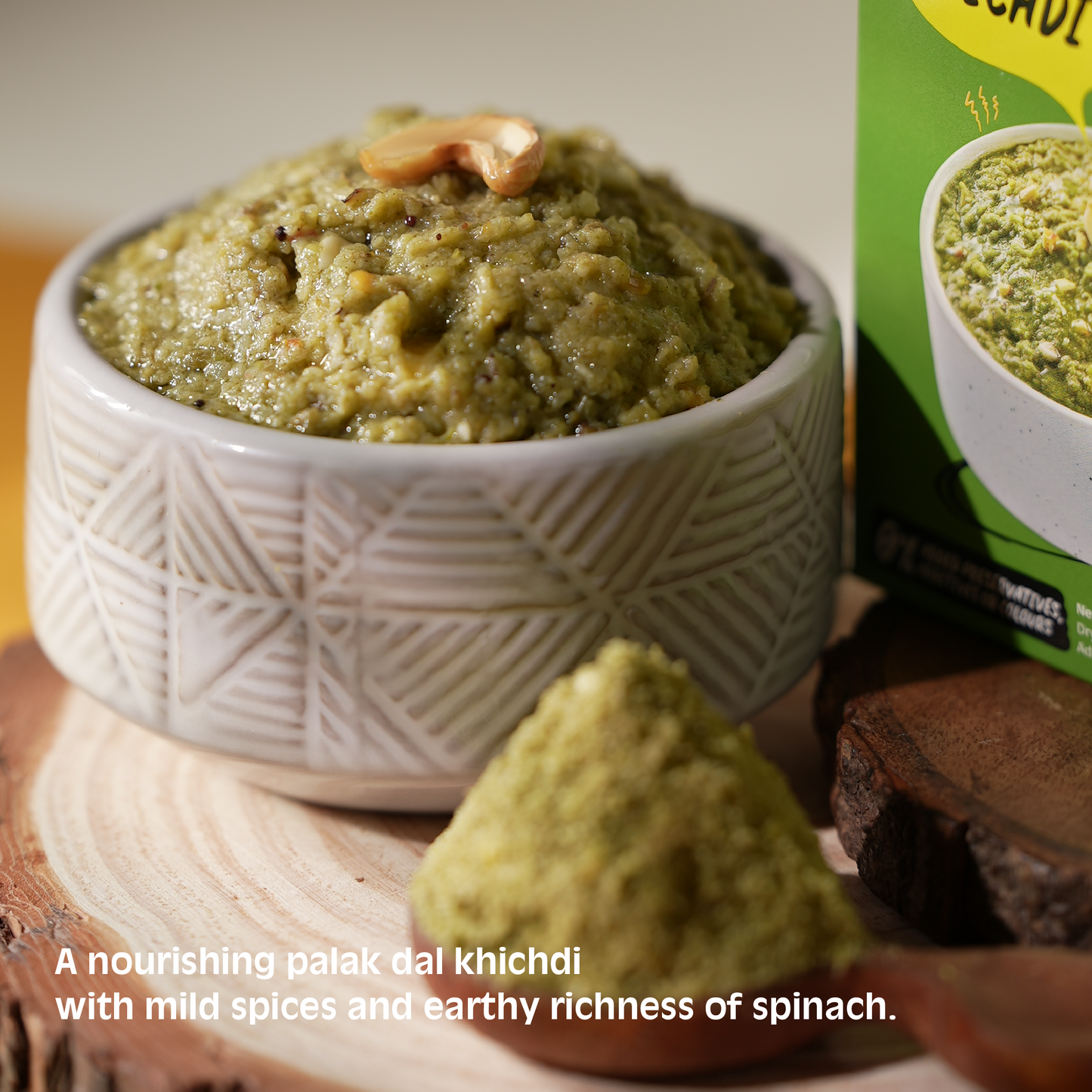Bowl of palak dal khichdi with a box in the background on a wooden surface